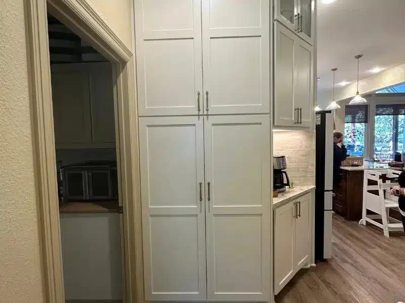 Tall white kitchen cabinets with pantry and coffee nook beside open living area, Austin, TX home