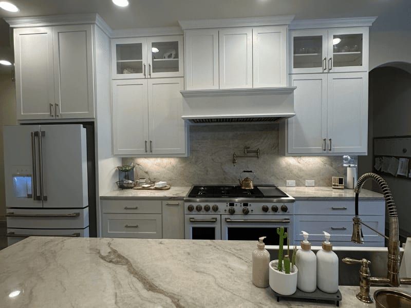 Kitchen with white cabinets to the ceiling, a marble slab backsplash, a pot filler and a double range