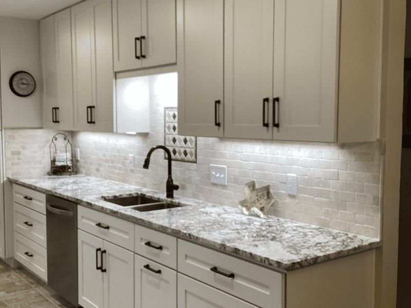 Kitchen run with white shaker cabinets, granite counters, a stone tile backsplash and a black faucet