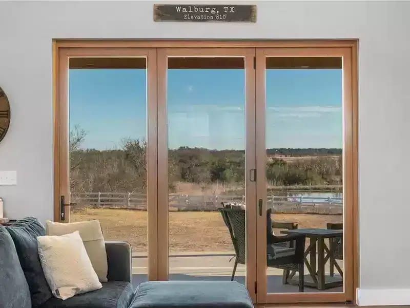 Living room with large wooden-framed glass doors in Appaloosa Way Custom Home in Austin, TX