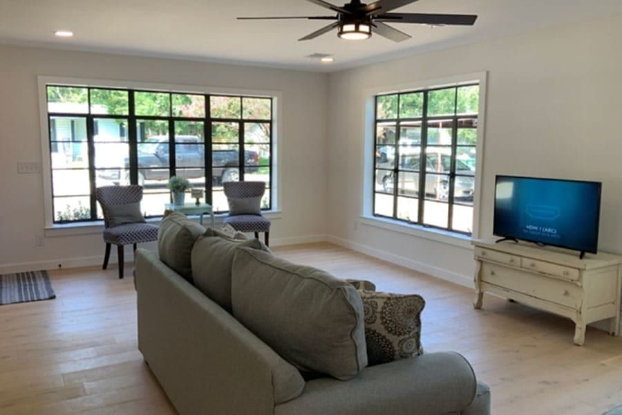 Living room with two walls of restored black steel casement windows and pale wood floors
