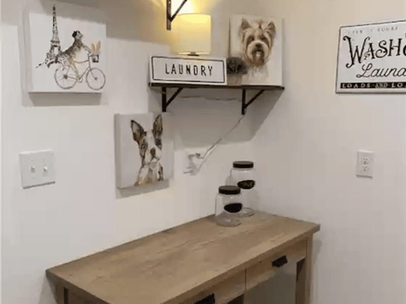 Laundry room with a wood folding counter, a bracket shelf and framed prints on white walls
