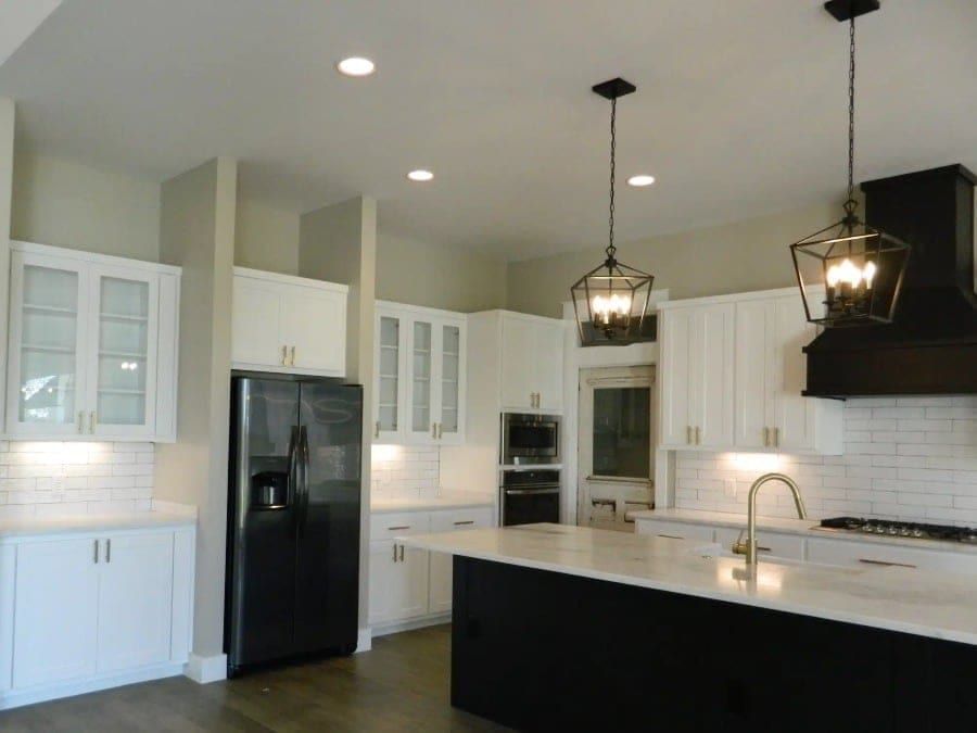 A modern kitchen featuring white cabinets & black appliances in Liberty Hills, TX
