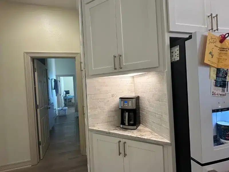 Kitchen coffee nook with white cabinets, espresso maker, and marble counter in Austin, TX home