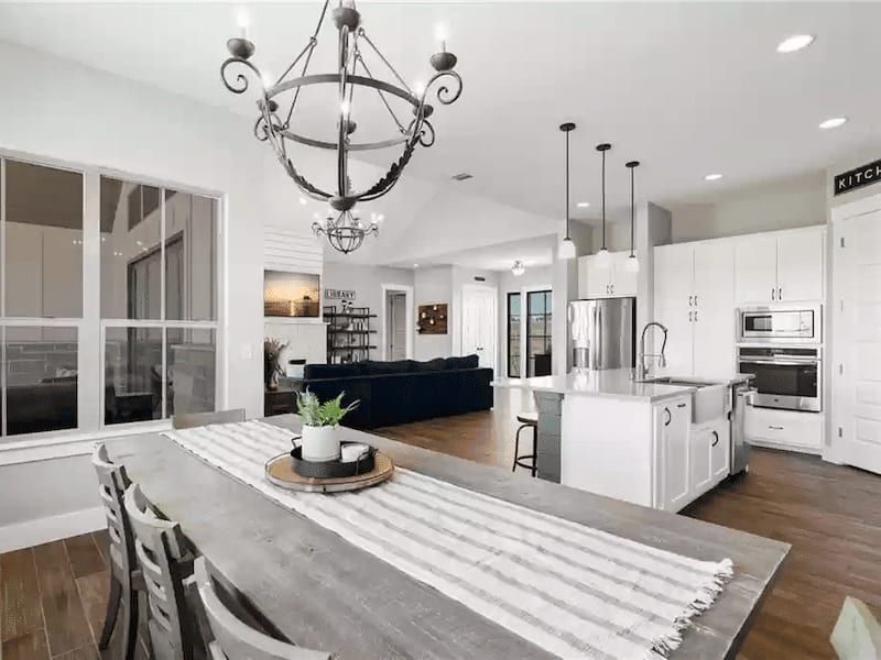 Bright open kitchen and dining with island, chandelier, and white cabinets in Austin, TX home