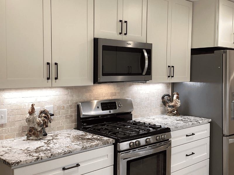 Range wall with a stainless gas range, an over-range microwave and a stone tile backsplash