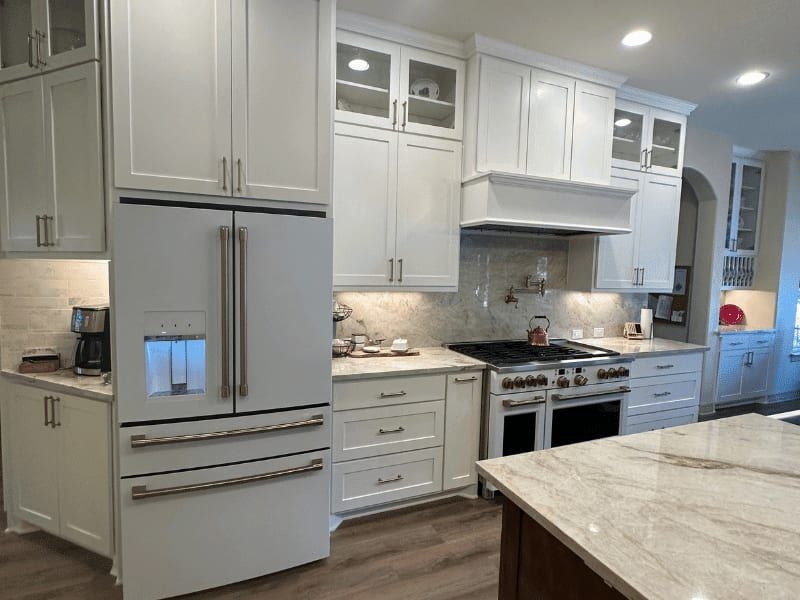 Kitchen with a panelled refrigerator, white cabinets, a double range and a marble slab backsplash
