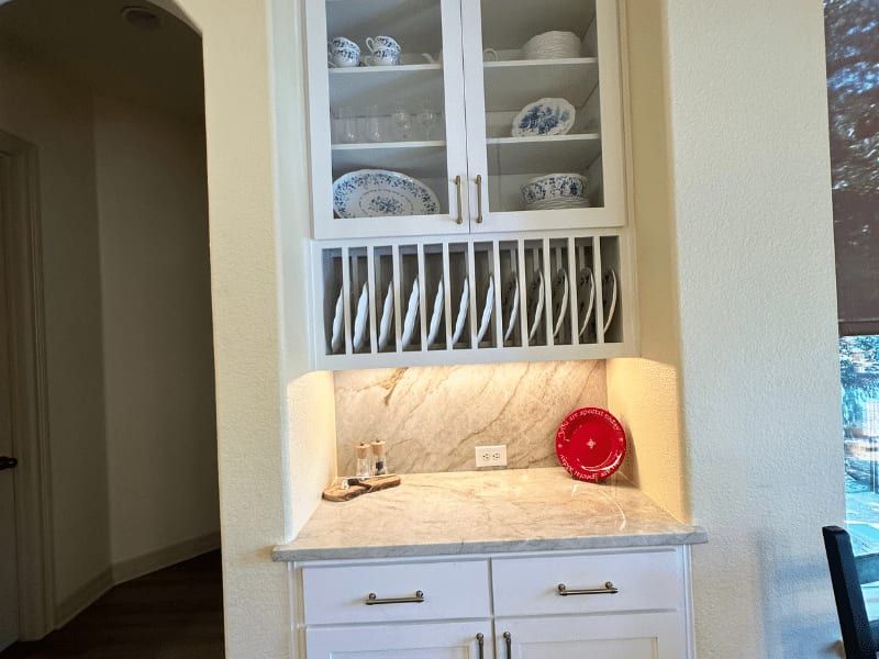 Built-in kitchen hutch with glass cabinets, plate rack, and marble counter in Austin, TX home