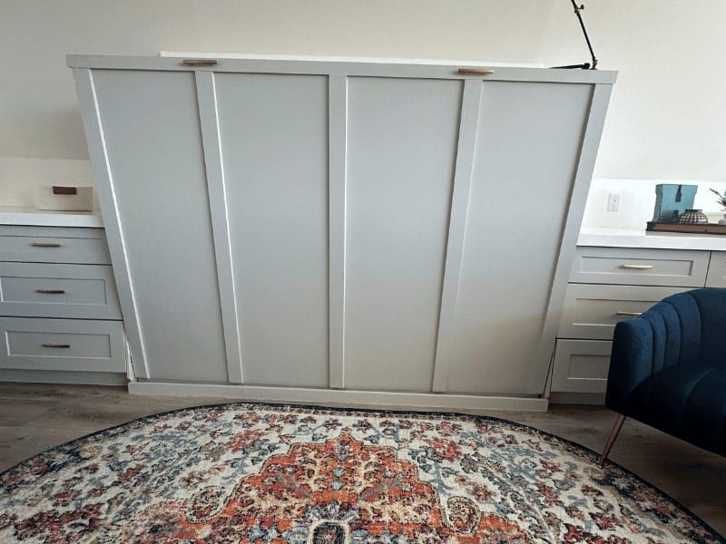 Murphy bed closed into its cabinet between built-in drawers, in the game room above the garage