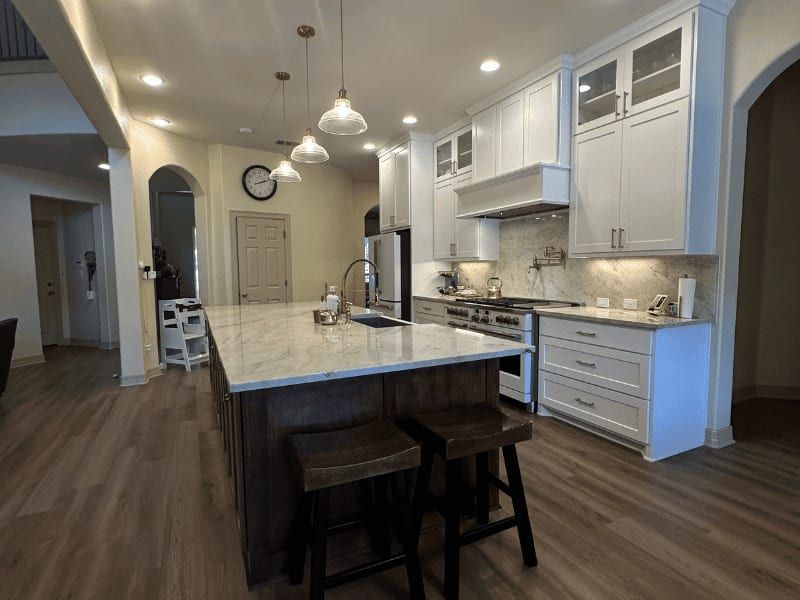 Kitchen after the columns came out, with a long dark island in marble and an open view through the house