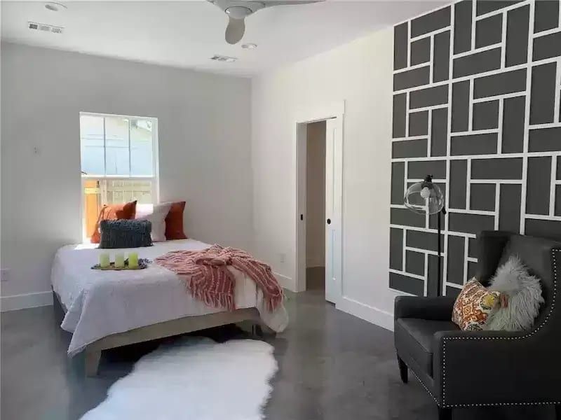 Modern bedroom with accent wall and seating area in a home in Austin, TX