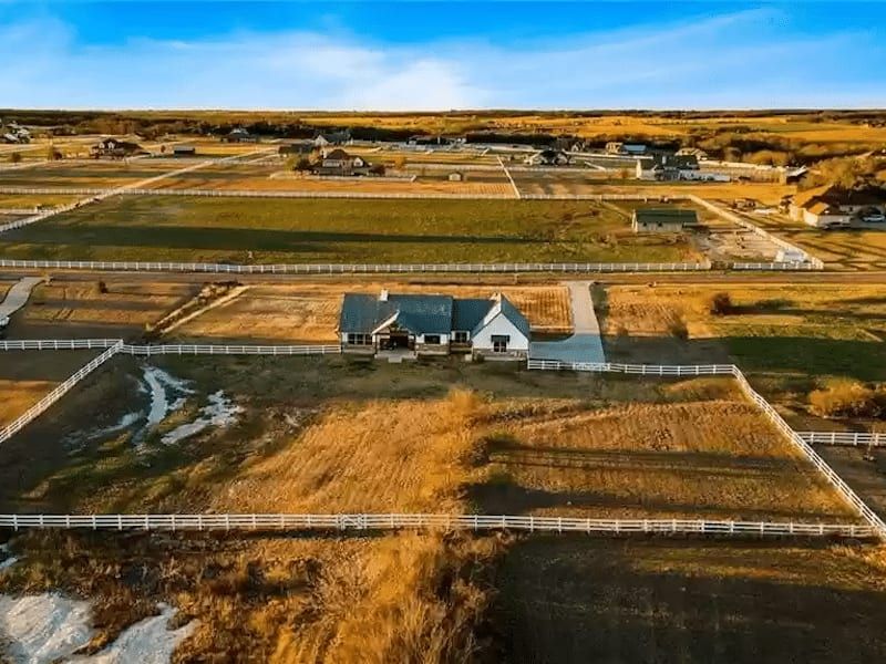 Aerial view of the house on the last lot in the community, surrounded by fenced acreage
