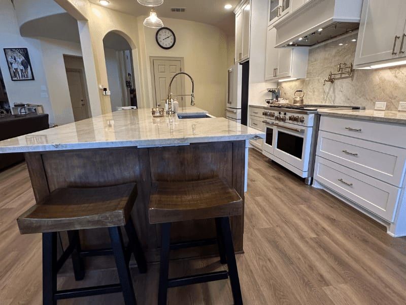 Dark wood island with a marble top and saddle stools, looking toward the range wall