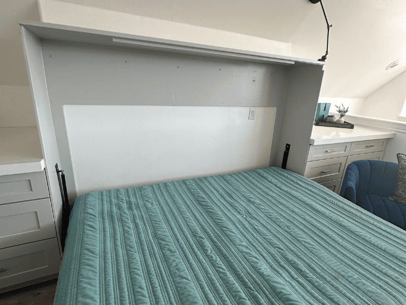 Murphy bed folded down and made up, with built-in cabinets and a desk to either side
