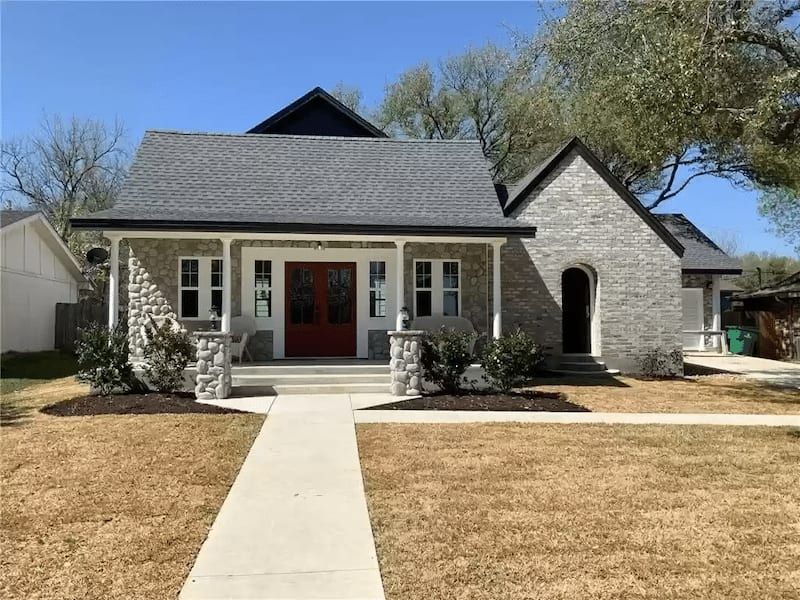 Custom Home in North Lynn with stone exterior, red door, and spacious front yard