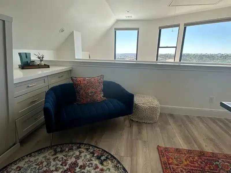 Upstairs loft sitting area with blue chair, windows, and built-in cabinets in Austin, TX home