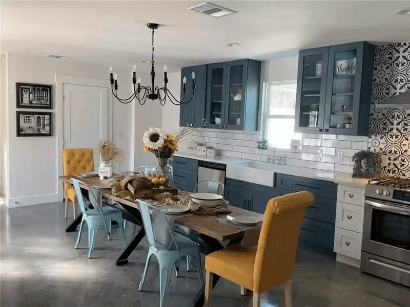 Kitchen and dining area with navy cabinets, white subway tile, a farmhouse sink and patterned tile behind the range