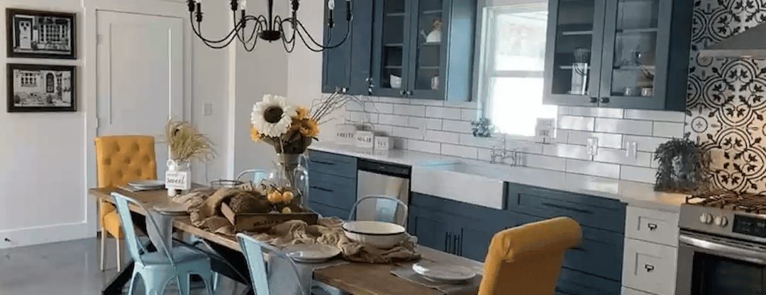 Kitchen and dining area with navy cabinets, white subway tile, a farmhouse sink and patterned tile behind the range