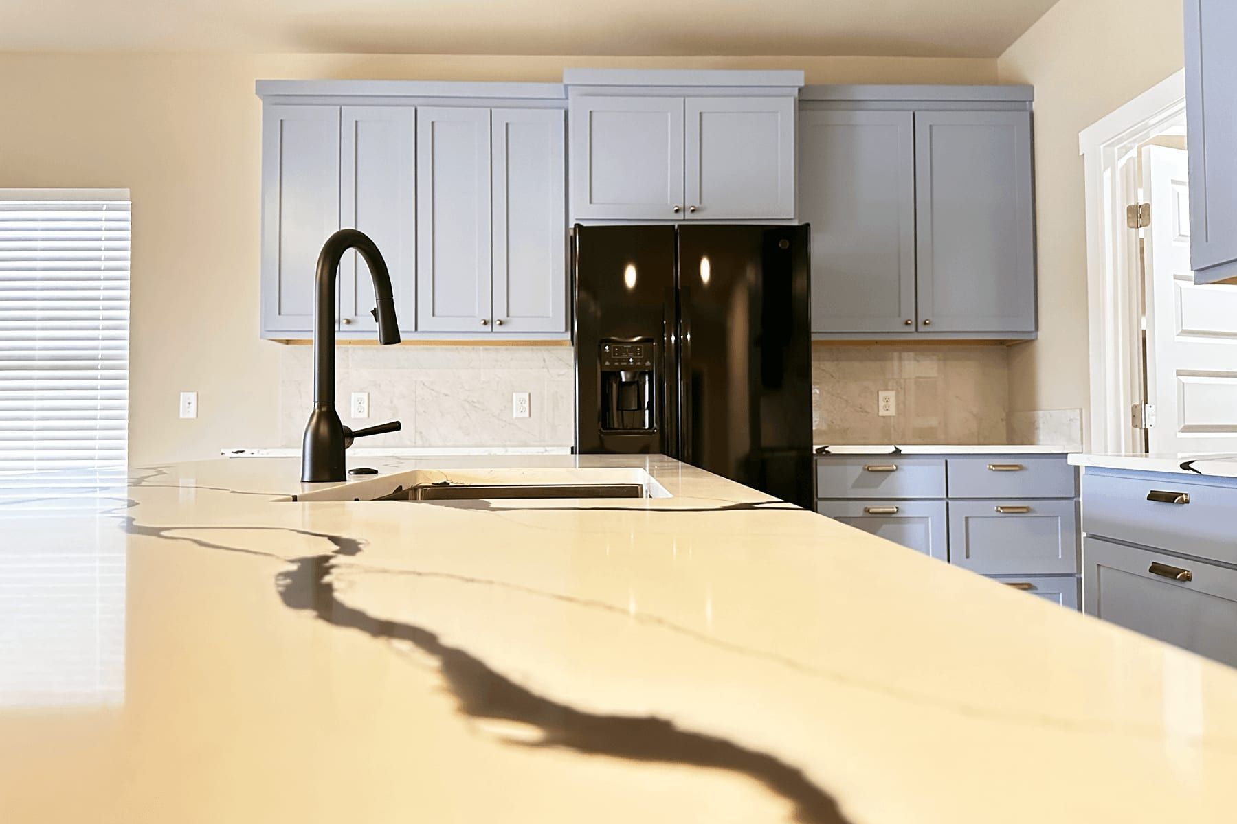 Custom light-gray shaker cabinetry with a veined quartz island in a Round Rock kitchen