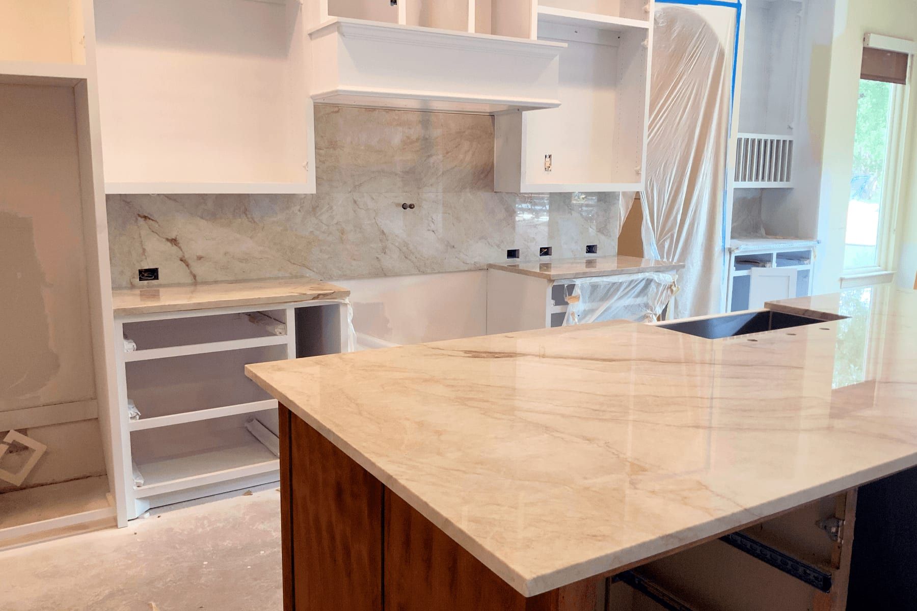 Kitchen mid-build in Leander: island counter set, cabinets masked for finishing