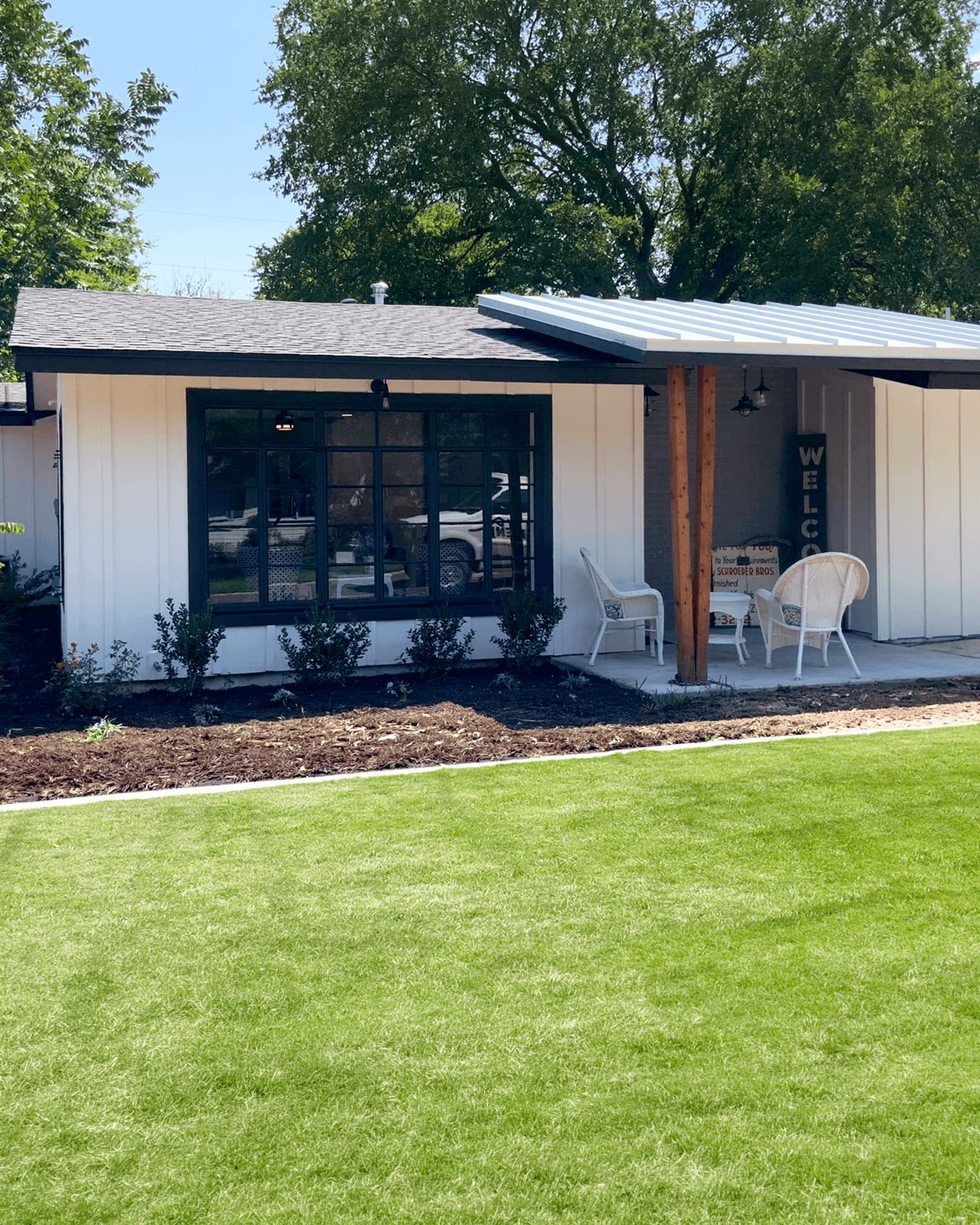 The same house after the whole-home remodel, with new board-and-batten siding, black-framed windows, and a covered porch