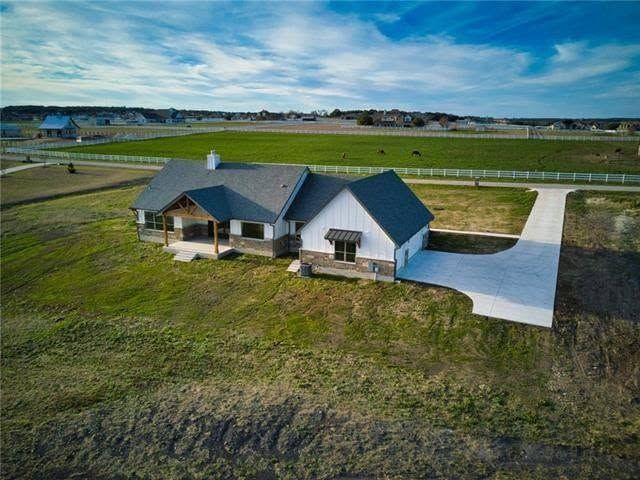 A finished Flenn custom home on its lot, seen from above, with pasture and fence line behind