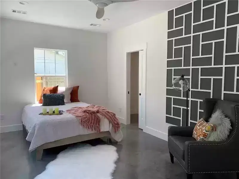 Modern bedroom with accent wall and seating area in a home in Austin, TX<br />
